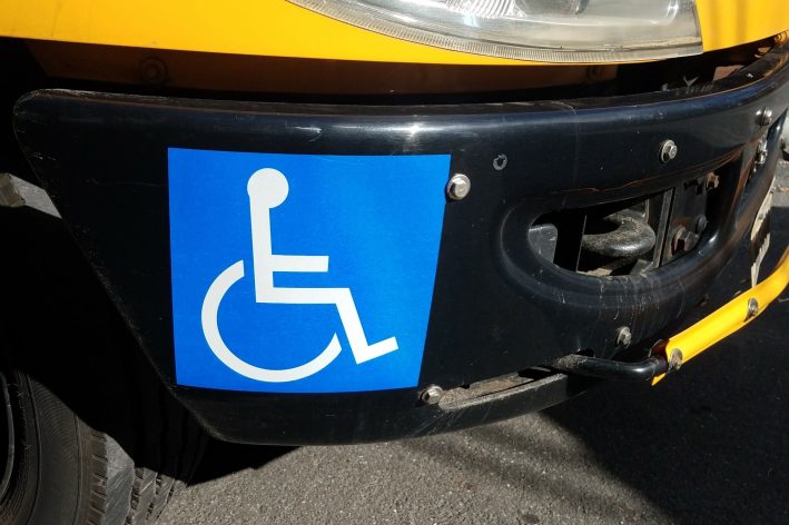 blue wheelchair or disabled or handicapped symbol or sign on yellow school bus bumper
